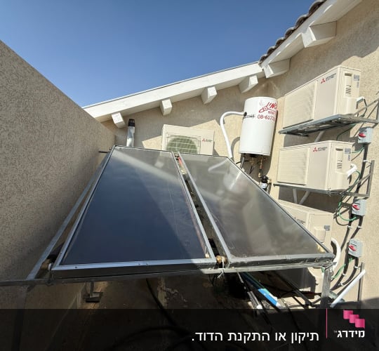 מערכת סולארית עם קולטי שמש ומזגנים מותקנים על קיר חיצוני